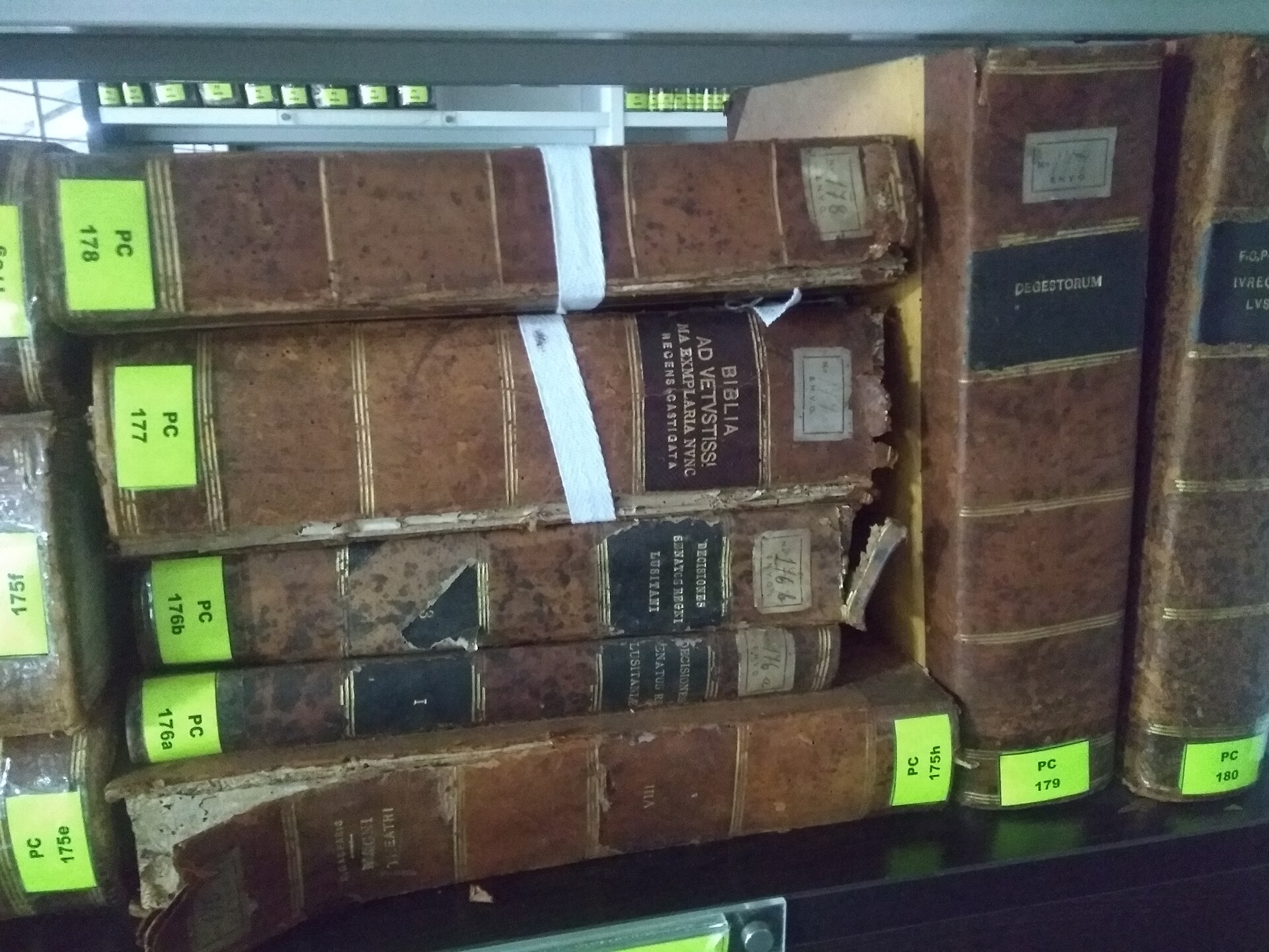 Ряд старинных книг в кожаных переплётах на полке, часть с повреждёнными корешками